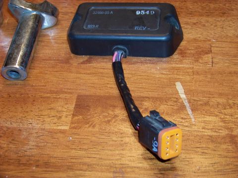 1995 Mercury Grand Marquis - A close-up view of an electronic control module and its wiring harness, resting on a wooden surface.