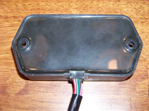 1995 Mercury Grand Marquis - A black electronic component with a multi-colored wire harness is shown close-up on a wooden background.