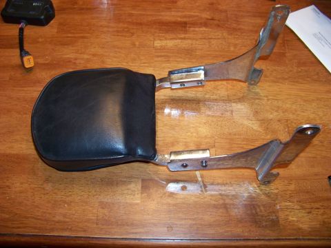 1995 Mercury Grand Marquis - A black motorcycle passenger backrest with chrome mounting hardware and an electronic control module is displayed on a wooden surface.