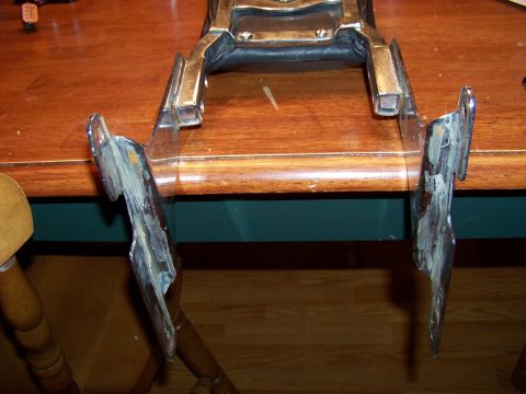 1995 Mercury Grand Marquis - Chrome trim piece with damage and residue, likely a car part, on a table.
