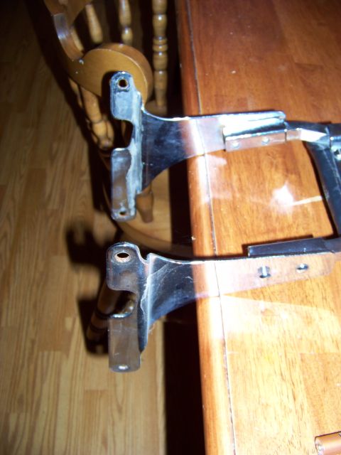 1995 Mercury Grand Marquis - These chrome-plated car parts are resting on a wooden table next to a chair.