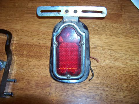 1995 Mercury Grand Marquis - A vintage tail light assembly with a chrome bezel and red lens is shown on a wooden surface.