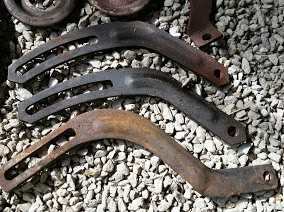 1968 Ford Torino - Three rusty metal brackets are displayed on a bed of gravel, with the SuperMotors.net logo visible at the bottom.