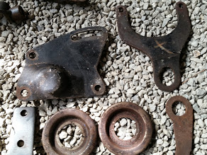 1968 Ford Torino - Assortment of old automotive parts, including brackets and circular pieces, displayed on gravel.