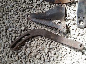 1968 Ford Torino - Two metal brackets are shown resting on a bed of gravel, with the Super Motors logo visible in the lower portion of the image.