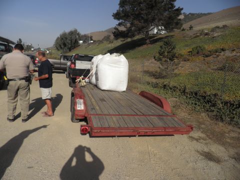 1994 Ford F-250 - A trailer and pickup truck are parked on a dirt road, with two men standing nearby.