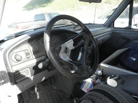 1994 Ford F-250 - The interior of a 1994 Ford F-250 shows a damaged steering wheel and dashboard, with another truck visible through the windshield.