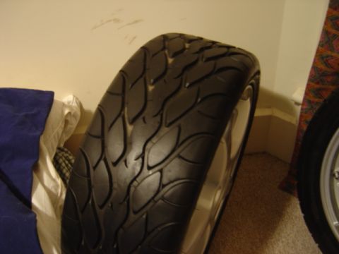 1998 Ford Taurus - A performance tire with a distinctive flame-like tread pattern is shown mounted on a silver rim.