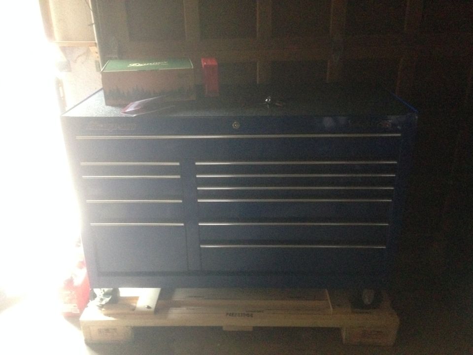 Blue toolbox with silver drawer pulls on a wooden pallet
