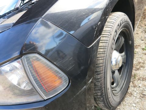 1991 Ford LTD Crown Victoria - Close-up view of a black car's front fender and tire, showing visible scratches on the paintwork.