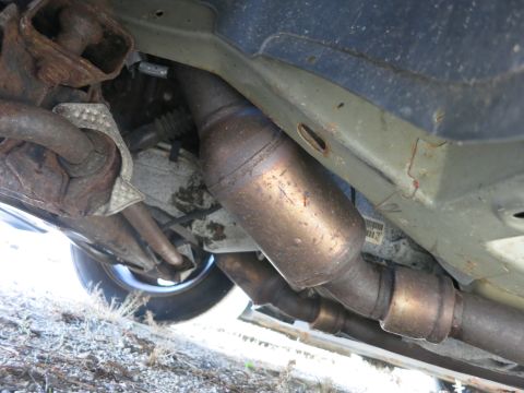 1991 Ford LTD Crown Victoria - The undercarriage of a vehicle reveals its exhaust system components, including the catalytic converter and piping.