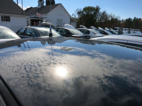 1991 Ford LTD Crown Victoria - The sun and clouds are reflected on the shiny surface of a car's roof, with a row of vehicles behind it.