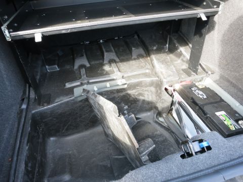 1991 Ford LTD Crown Victoria - The trunk interior of a vehicle, revealing the battery and surrounding carpeting.