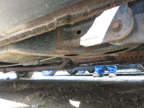 1991 Ford LTD Crown Victoria - Close-up of rusted undercarriage components and exhaust system on a vehicle.