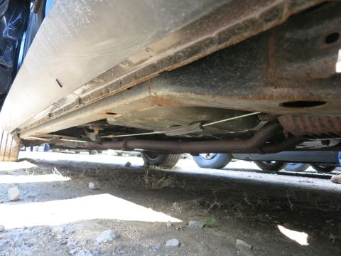 1991 Ford LTD Crown Victoria - The undercarriage of a vehicle shows its exhaust system and frame components, with visible signs of wear and rust.