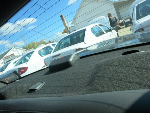 1991 Ford LTD Crown Victoria - Several white sedans are parked in a lot under a blue sky with clouds.