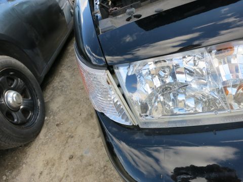 1991 Ford LTD Crown Victoria - Close-up of a black car's front corner, showing the headlight and turn signal assembly.