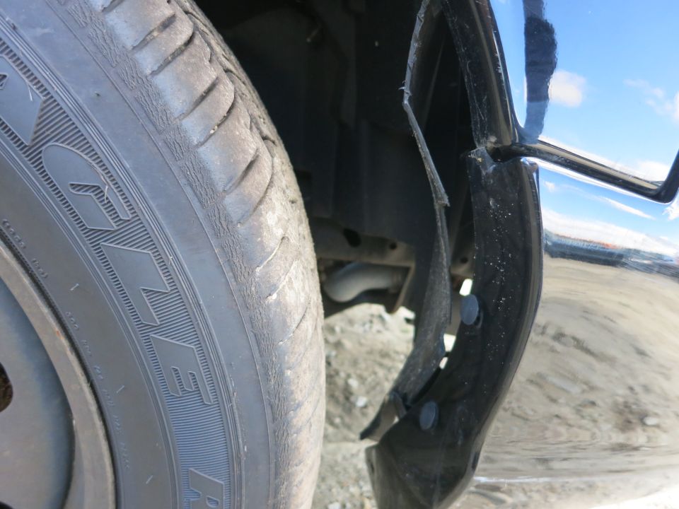Close-up of a car's wheel well and detached fender flare