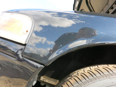 1991 Ford LTD Crown Victoria - The reflection in the fender shows a person and the sky with clouds.