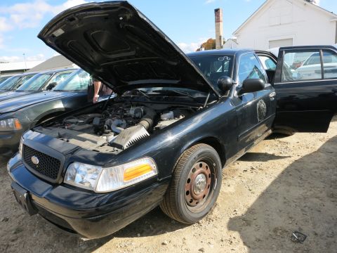 1991 Ford LTD Crown Victoria - A black police car sits with its hood open, revealing the engine compartment. Another vehicle is visible behind it.