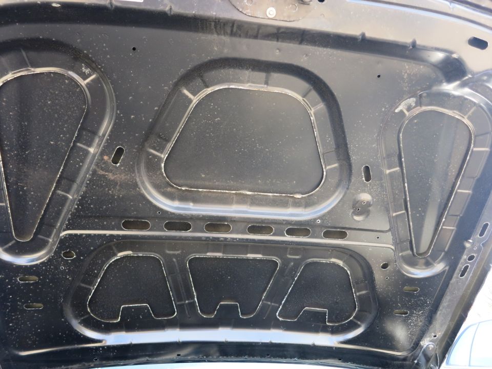 Underside of a car hood with sound-dampening material and structural supports