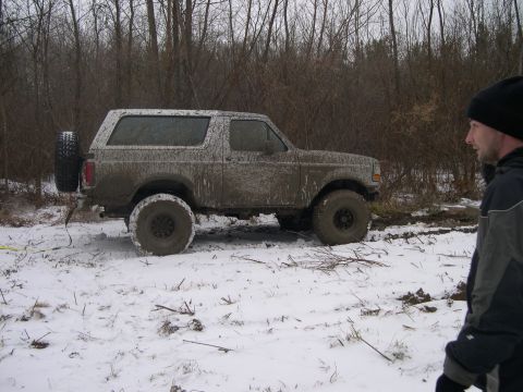 1995 Ford Bronco - This mud-covered 1992 Ford Bronco navigates a snowy, wooded terrain, its off-road capabilities.