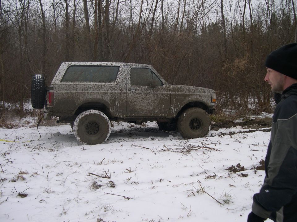Mud-covered 1992 Ford Bronco in snow, side view. Spare tire on rear