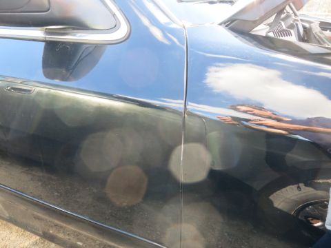 1991 Ford LTD Crown Victoria - Close-up of a dark sedan's side panel, showing the seam between the door and fender.