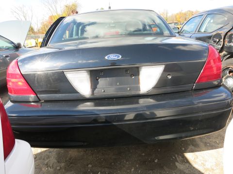 1991 Ford LTD Crown Victoria - This Ford Crown Victoria is parked in a lot with other vehicles, showing its rear end.