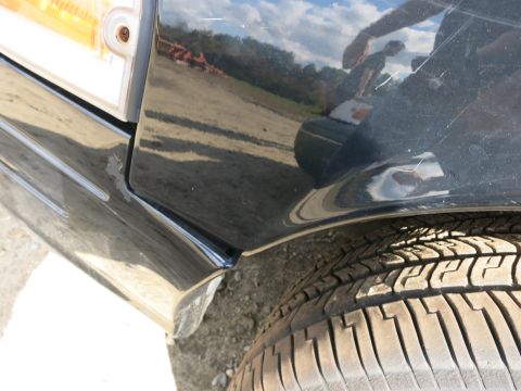 1991 Ford LTD Crown Victoria - The front corner of a black vehicle shows a portion of the fender and a tire.
