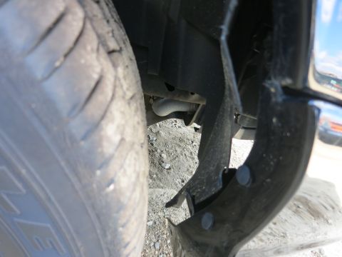 1991 Ford LTD Crown Victoria - A close-up view shows a worn tire and a damaged fender liner, revealing the undercarriage of a vehicle.