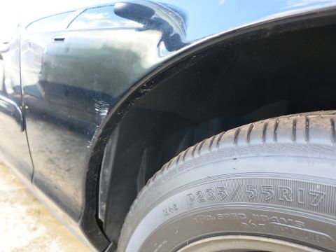 1991 Ford LTD Crown Victoria - Detail shot of a tire and wheel well on a dark-colored vehicle.