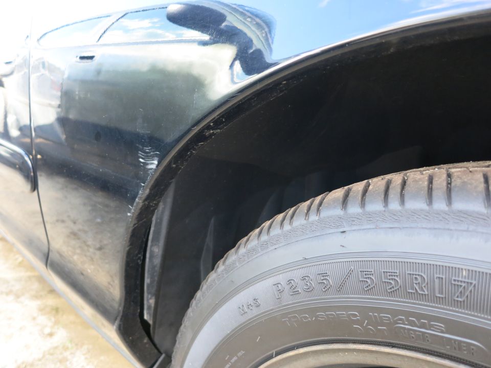 Close-up of a car's wheel well and tire with P235/55R17 markings