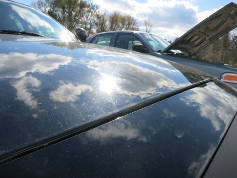 1991 Ford LTD Crown Victoria - Two cars are parked outside under a cloudy sky, with one car's hood open.