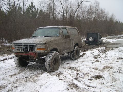 1995 Ford Bronco - Two off-road vehicles are stuck in the mud and snow, with one being towed.