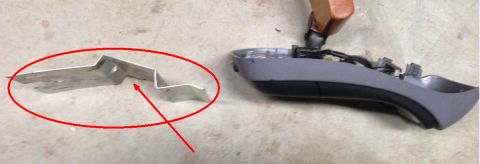 1993 Ford Bronco - A metal bracket and a car's interior trim piece are shown on a concrete surface.