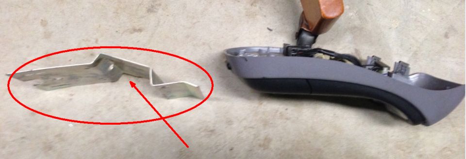 Metal bracket and gray car interior trim piece on concrete floor