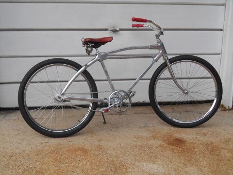 Chrome cruiser bicycle side view with red grips and seat