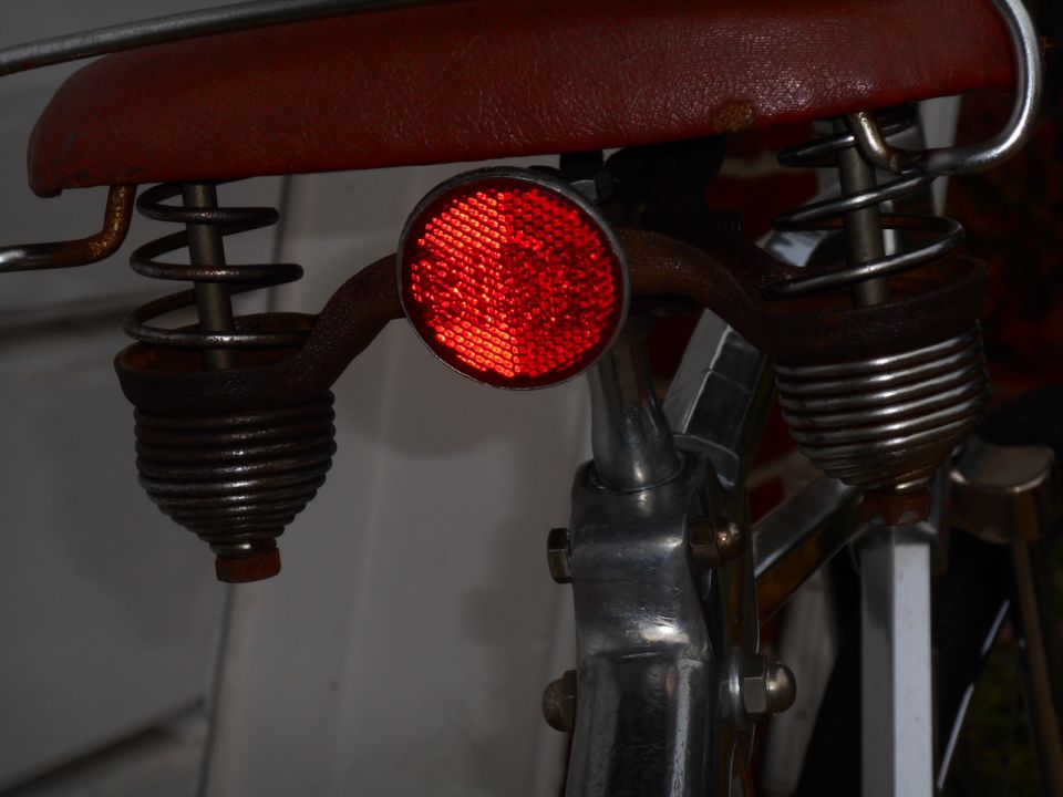 Red bicycle saddle with chrome springs and a red reflector on the seat post