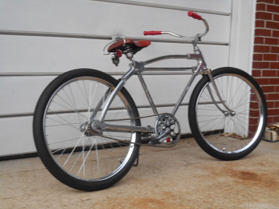 Chrome cruiser bicycle with red handlebars and seat, side view