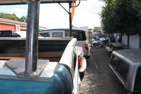 1994 Ford F-250 - A view from inside a pickup truck bed, showing a rack and other vehicles parked nearby in an outdoor lot.