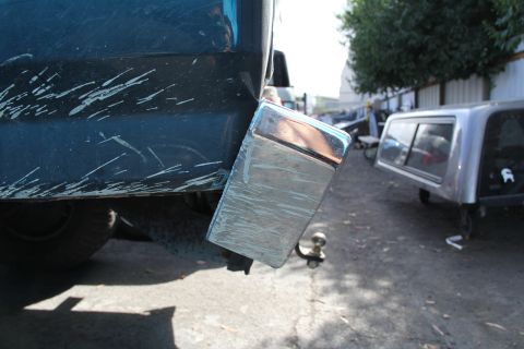 1994 Ford F-250 - Close-up of a truck's rear bumper and tow hitch, with other vehicles and a truck cap visible in the background.