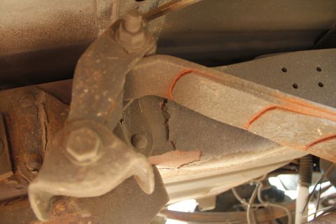 1994 Ford F-250 - Detail of a heavily rusted suspension part, showing wear and tear on the vehicle's undercarriage.