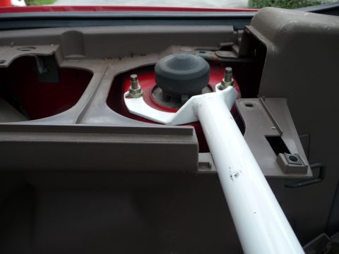 1993 Mazda MX-3 - Close-up view of a white strut bar installed in the interior of a red vehicle.