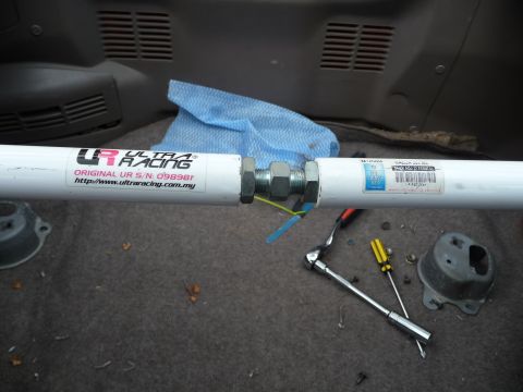 1993 Mazda MX-3 - A white Ultra Racing strut bar is shown with its serial number and website printed on it, alongside various tools.