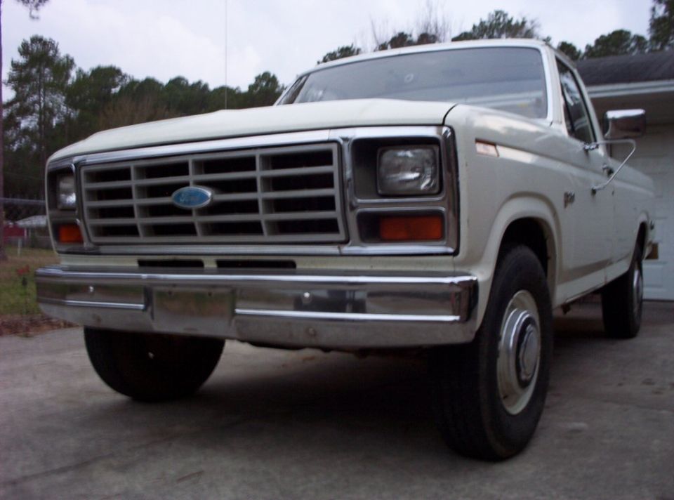 Front view of a white 1980s Ford F-Series truck with a chrome grille and bumper