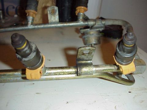 1989 Ford Bronco - Close-up view of a fuel rail assembly with multiple fuel injectors attached.