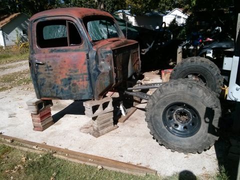 1986 Ford Bronco - This heavily rusted truck cab is elevated on cinder blocks, revealing its chassis and large off-road tires.
