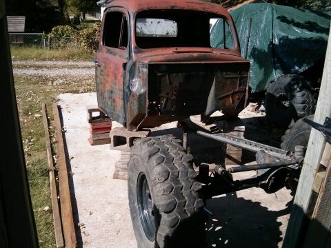 1986 Ford Bronco - This old truck cab is undergoing restoration, sitting on blocks with large tires visible.