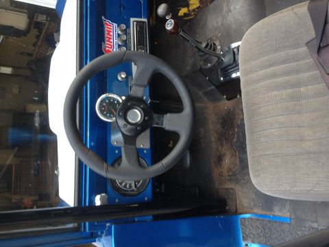 1974 Ford Bronco - Interior view of a blue vehicle's dashboard and driver's seat, showing aftermarket modifications.